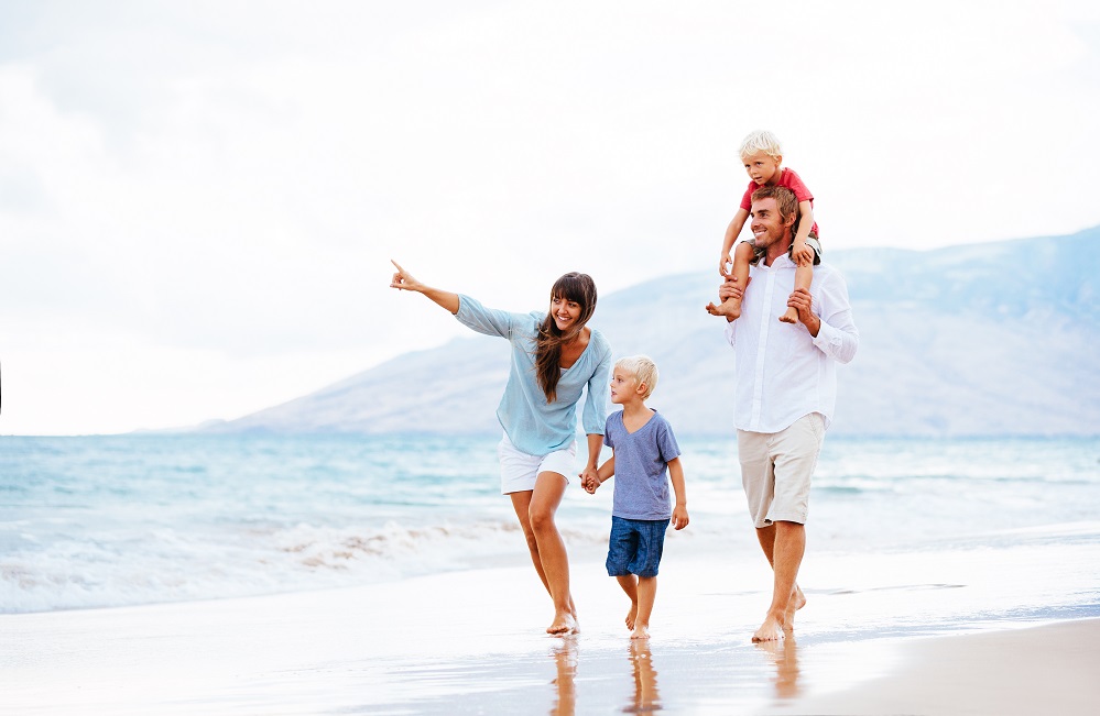 Happy Young Family Walking Down the Beach at Sunset