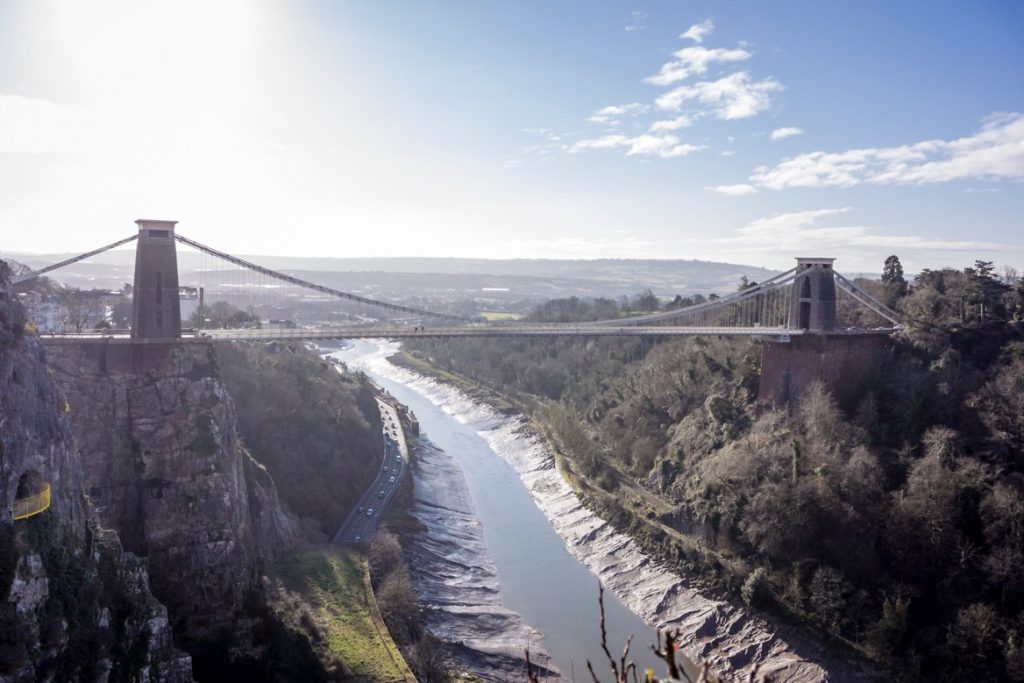 A bridge over a body of water with a mountain in the background

Description automatically generated