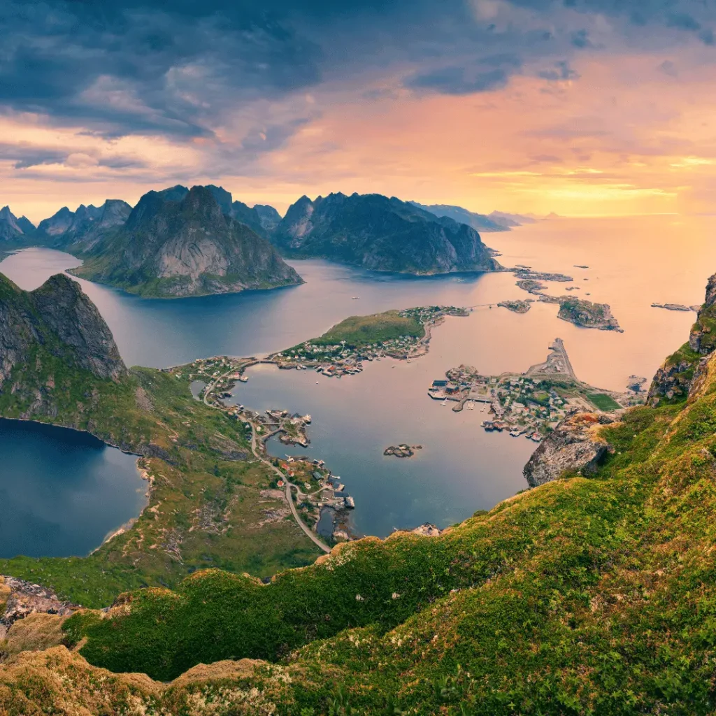 Aerial view of coastal islands, fjords, and mountains in Norway during sunset.