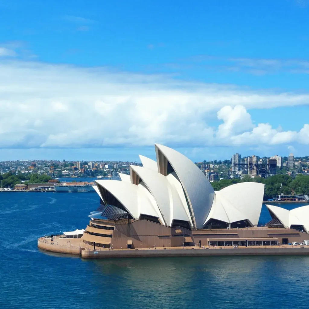 The Sydney Opera House surrounded by blue harbor water on a clear day.